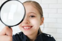 8-letnia uśmiechnięta dziewczynka w policyjnej koszulce z lupą w reku