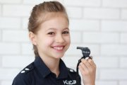 fotografia profilowa młodej dziewczynki w policyjnej koszuli i z policyjnym gwizdkiem w lewej dłoni