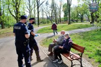 umundurowani policjanci rozdają mieszkańcom Tomaszowa maseczki ochronne