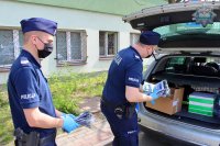 umundurowani policjanci rozdają mieszkańcom Tomaszowa maseczki ochronne