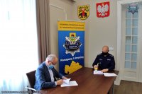 Komendant Powiatowy Policji w Tomaszowie Mazowieckim i Wójt Gminy Tomaszów siedzą przy stole konferencyjnym i podpisują umowę w sprawie służb ponadnormatywnych