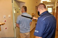 w pomieszczeniach dla osób zatrzymanych umundurowany policjant dokonuje kontroli wykrywaczem metali osoby zatrzymanej - mężczyzny