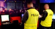 dwóch mężczyzn po lewej w kamizelce odblaskowej z napisem policja i po prawej w kamizelce odblaskowej z napisem służba celna wykonują oględziny automatu do gier hazardowych