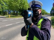 umundurowany policjant ruchu drogowego mierzy prędkość pojazdów ręcznym laserowym miernikiem prędkośći