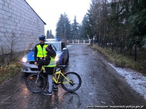 policjantka ruchu drogowego w ramach prowadzonych działań wręcza elementy odblaskowe pieszym i rowerzystom