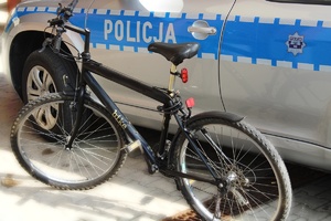 poglądowe zdjęcie roweru stojącego na tle oznakowanego radiowozu policji