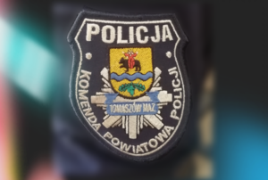 naszywka z napisem Policja Komenda Powiatowa Policji oraz policyjną gwiazdą i godłem powiatu tomaszowskiego, tło rozmyte