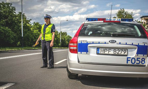 policjantka w mundurze stoi na drodze przy radiowozie