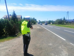 policjant stojący przy drodze z miernikiem prędkości