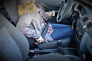 kobieta siedząca za kierownicą pojazdu zapina pasy bezpieczeństwa