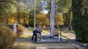 Komendanci w umundurowaniu wyjściowym na Cmentarzu wojennym składają znicze i hołd poległym policjantom