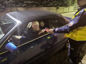 policjant ruchu drogowego przekazuje kobiecie siedzącej za kierownicą pojazdu serduszko w ramach prowadzonej akcji