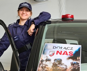 dziewczyna w mundurze ucznia klasy policyjnej stoi na progu pojazdu na  którego szybie czołowej jest plakat z treścią dołącz do nas