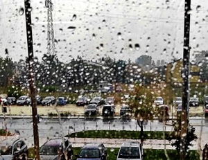 krople deszczu na szybie za oknem widoczny parking samochodowy