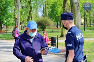 umundurowani policjanci rozdają mieszkańcom Tomaszowa maseczki ochronne