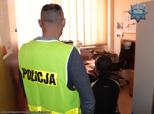 policjant prowadzi zatrzymanego na przesłuchanie