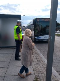 Policjant i pracownik sanepidu czekający na przystanku autobusowym