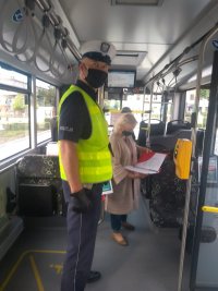 Policjant i pracownik sanepidu podczas kontroli przeprowadzenej w autobusie komunikacji miejskiej.