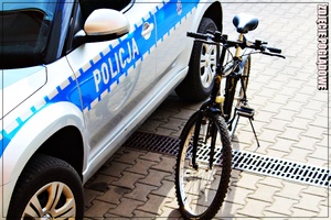 zdjęcie poglądowe roweru typu górski stojącego przy policyjnym, radiowozie