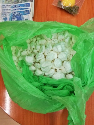 duża ilość narkotyków w postaci białego proszku w torbie foliowej i pieniądze rozłożone na blacie stołu