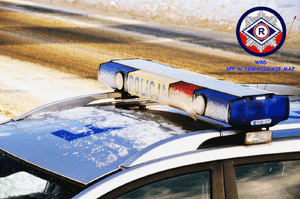 dach oznakowanego radiowozu z belką dzwiękowo błyskową, częściowo zaśnieżony , rozmyte tło - jezdnia