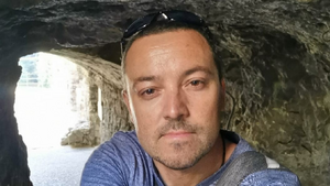 wizerunek mężczyzny w niebieskiej koszulce typu t-shirt  i okularami przeciwsłonecznymi  na czole