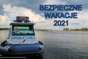 policyjna łódź motorowa z kabiną zacumowana na zbiorniku wodnym i napis koloru niebieskiego o treści bezpieczne wakacje 2021