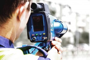 policjant ruchu drogowego mierzy prędkość ręcznym miernikiem