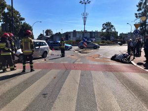 miejsce wypadku , widac drogę, rozbite auto i motocykl   oraz pracujące służby