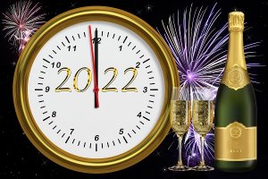 Na pierwszym planie okrągła tarcza zegara, na którym jest data 2022, a  wskazówki zbliżają się do godziny 12. Po prawej stronie ilustracji widnieją kieliszki oraz butelka wypełniona szampanem, w tle rozbłyskujące się kolorowe fajerwerki