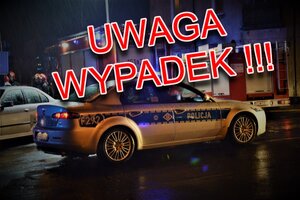 widok radiowozu policyjnego i w tle wozów bojowych straży pożarnej. na froncie napis Uwaga wypadek w kolorze czerwonym
