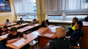 uczniowie siedzący w ławkach piszą w obecności komisji test wiedzy