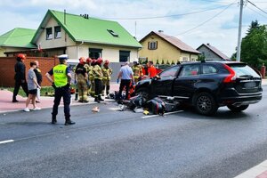 miejsce wypadku drogowego, przewrócony motorower i stojący obok pojazd osobowy. działania obecnych na miejscu służb