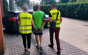 policjanci prowadzą do radiowozu zatrzymanego mężczyznę