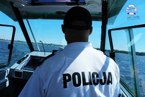 policyjny wodniak steruje motorową łodzią służbową