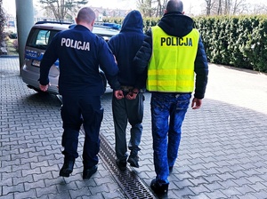 policjanci prowadzą zatrzymanego mężczyznę do radiowozu