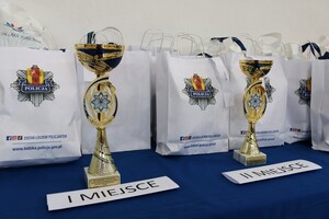 na stole stoją puchary i torby z nagrodami