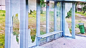 zdjęcie wiaty przystankowej o konstrukcji metalowej z szybami. trzy szyby stłuczone, drobne szkło leży na kostce brukowej