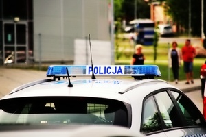 zdjęcie radiowozu z tyłu w tle widoczni ludzie, tło rozmazane