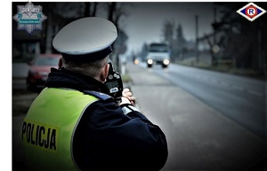 policjant ruchu drogowego mierzy prędkość laserowym miernikiem w lewym górnym rogu policyjna gwiazda z napisem policja, w prawym górnym rogu logo wydziału ruchu drogowego litera R wpisana w romb