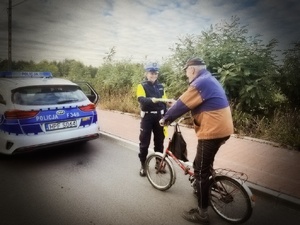 umundurowani policjanci ruchu drogowego rozdają niechronionym uczestnikom ruchu drogowego elementy odblaskowe