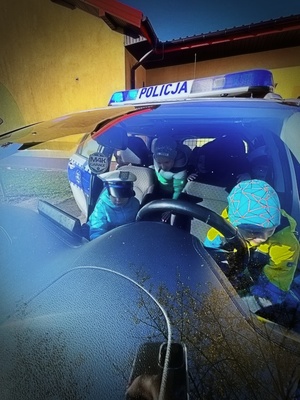 policjanci ruchu drogowego pokazują dzieciom wnętrze policyjnego radiowozu