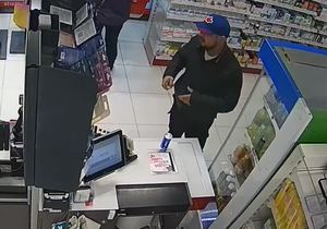 wizerunek osoby podejrzewanej o oszustwo. Mężczyzna z brodą w czarnej kurtce i spodniach oraz czapce z daszkiem na terenie sklepu