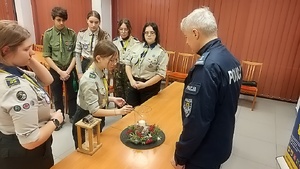 harcerze zapalają świecę w stroiku świątecznym przekazując ogień z Betlejem