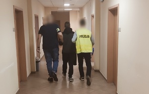 policjanci prowadzą pomiędzy sobą mężczyznę zatrzymanego za kradzieże