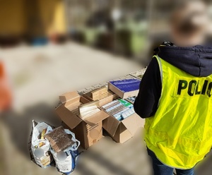 policjantka w odblaskowej kamizelce wykonuje spis zabezpieczonego tytoniu, papierosów i alkoholu bez polskich znaków akcyzy