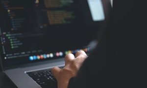 dłonie na klawiaturze komputera, częściowo widoczny ekran komputera