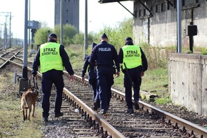 policjanci i strażnicy ochrony kolei wraz z psem służbowym patrolują obszary kolejowe