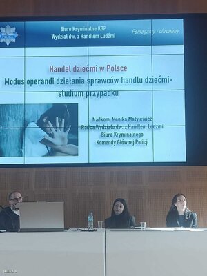 osoby siedzące za stołem konferencyjnym nad głowami obraz wyświetlany z prezentacji multimedialnej