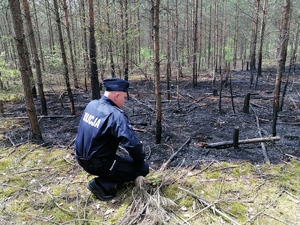 Policjant wykonuje oględziny miejsca pożaru